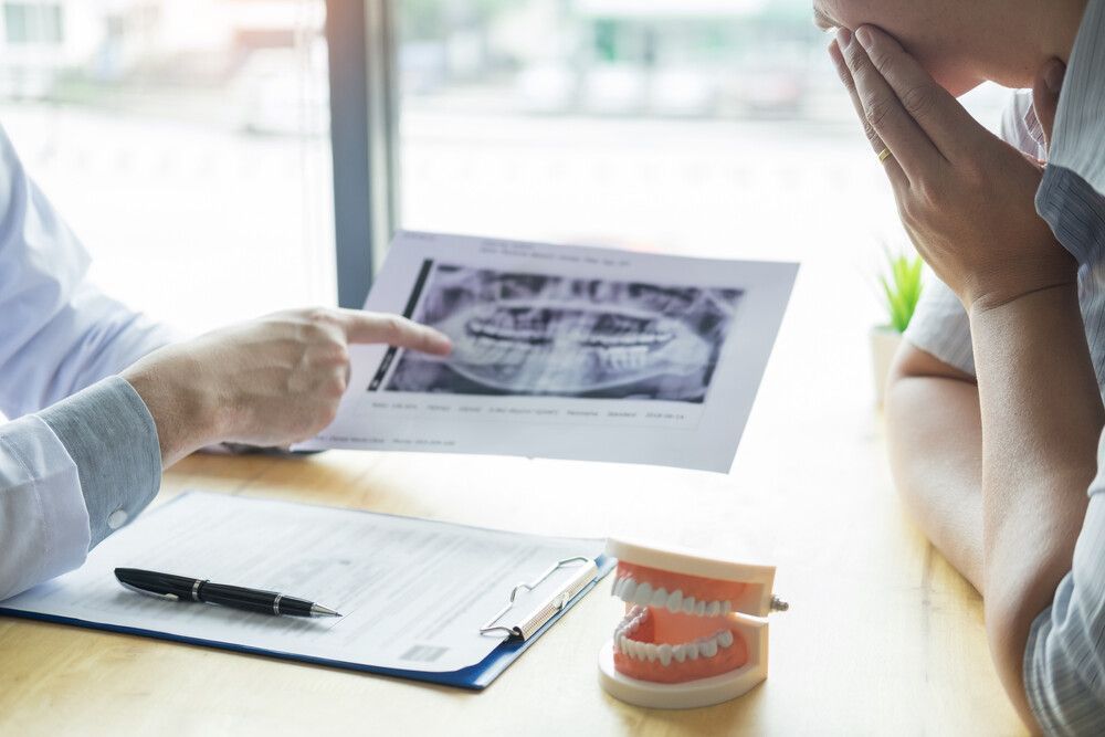 Un dentista señala una radiografía de los dientes de un paciente.