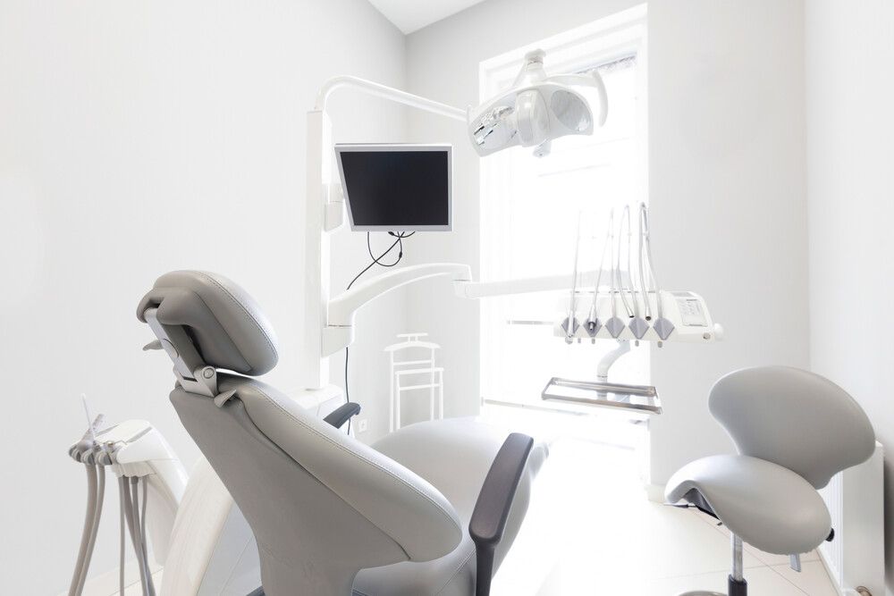 Un consultorio dental con un sillón dental y una ventana.