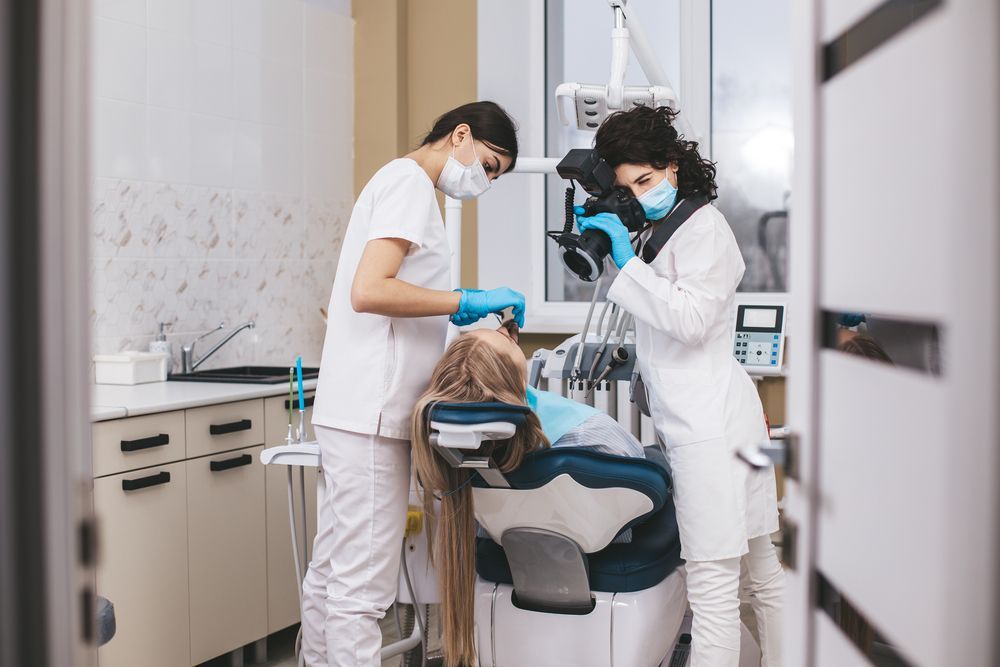 Un dentista y una enfermera están examinando los dientes de un paciente en un consultorio dental.
