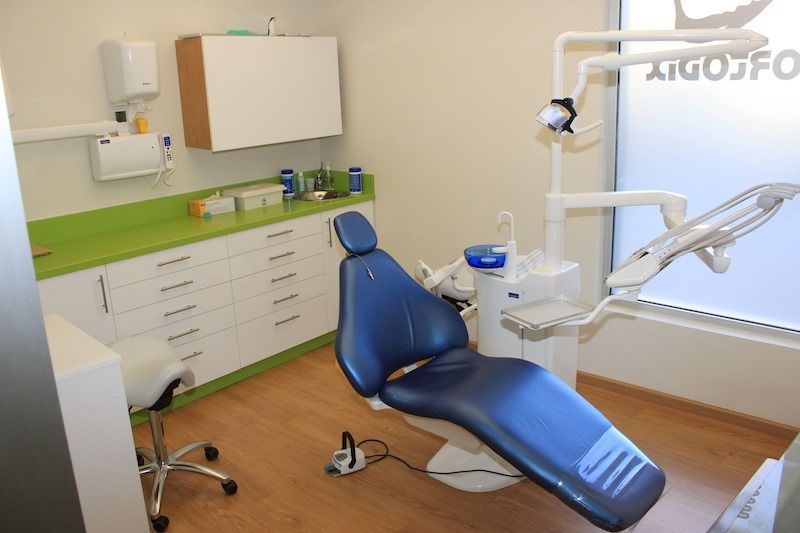 Un consultorio dental con una silla azul y una encimera verde.