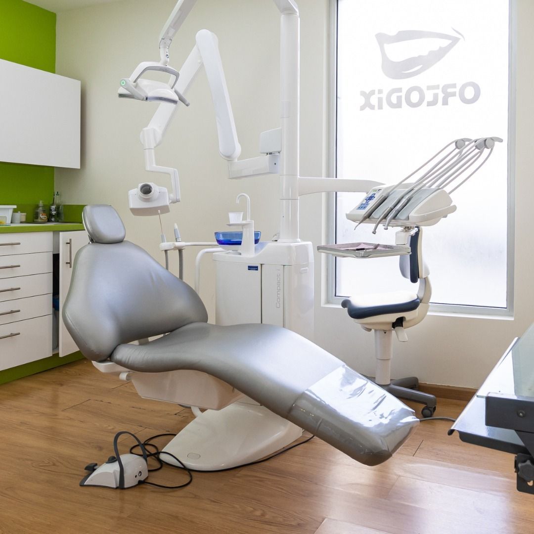 Un consultorio dental con una silla gris y una ventana que dice 'xigo'.