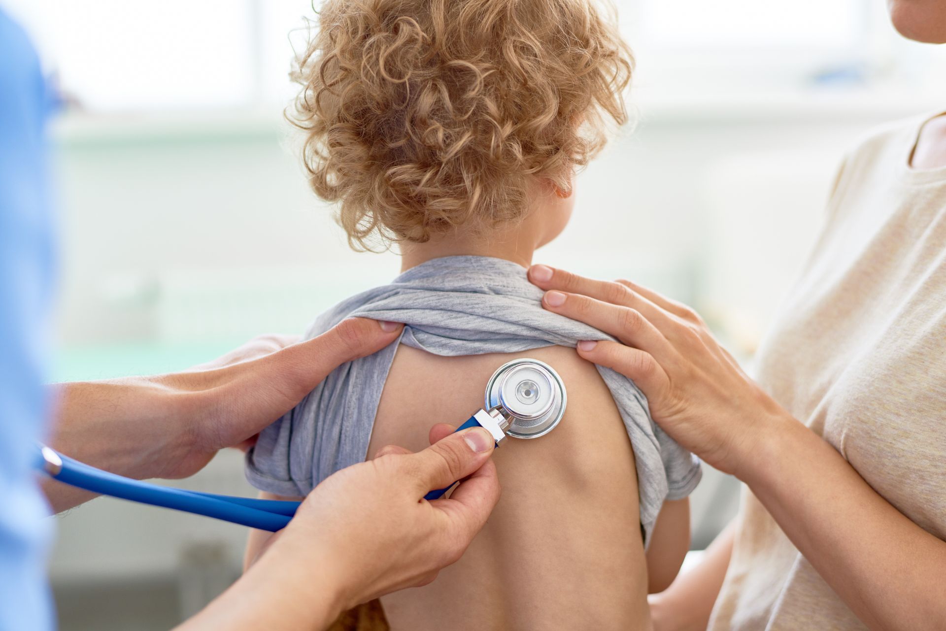Un jeune enfant bouclé se fait ausculter