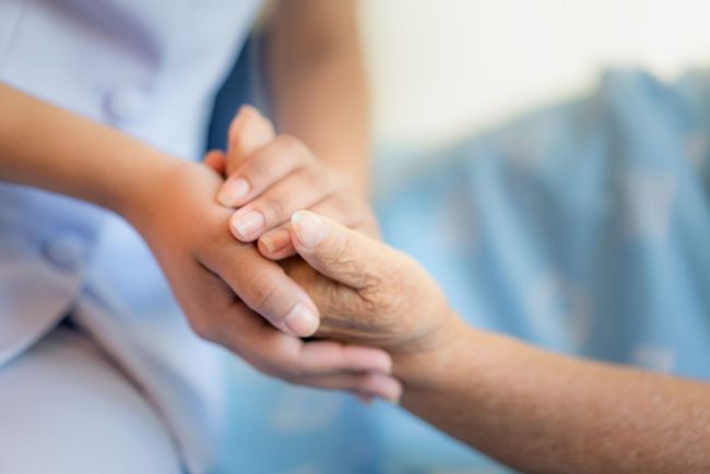 Une personne âgée donne sa main à une infirmière