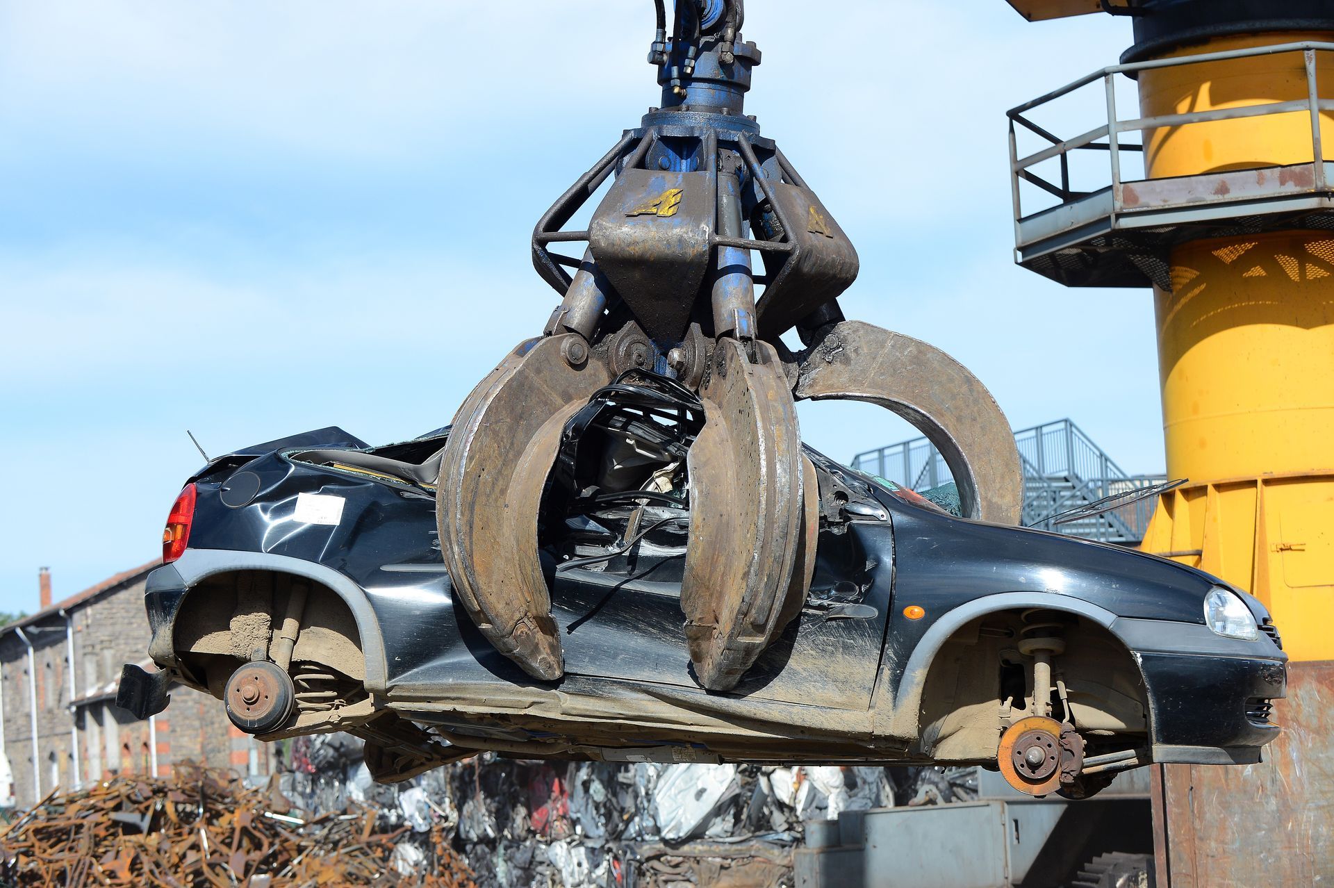 Une pince de grue enserre un épave de voiture.