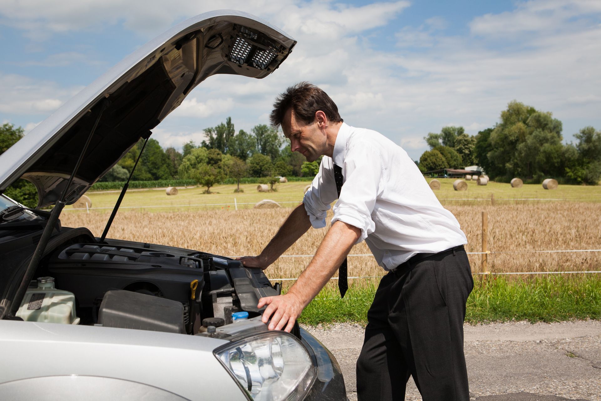 Un homme regarde le moteur d'un véhicule, le capot levé.