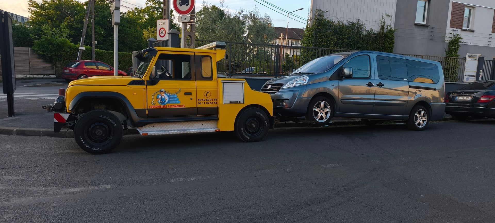 Une dépanneuse jaune remorque un van.