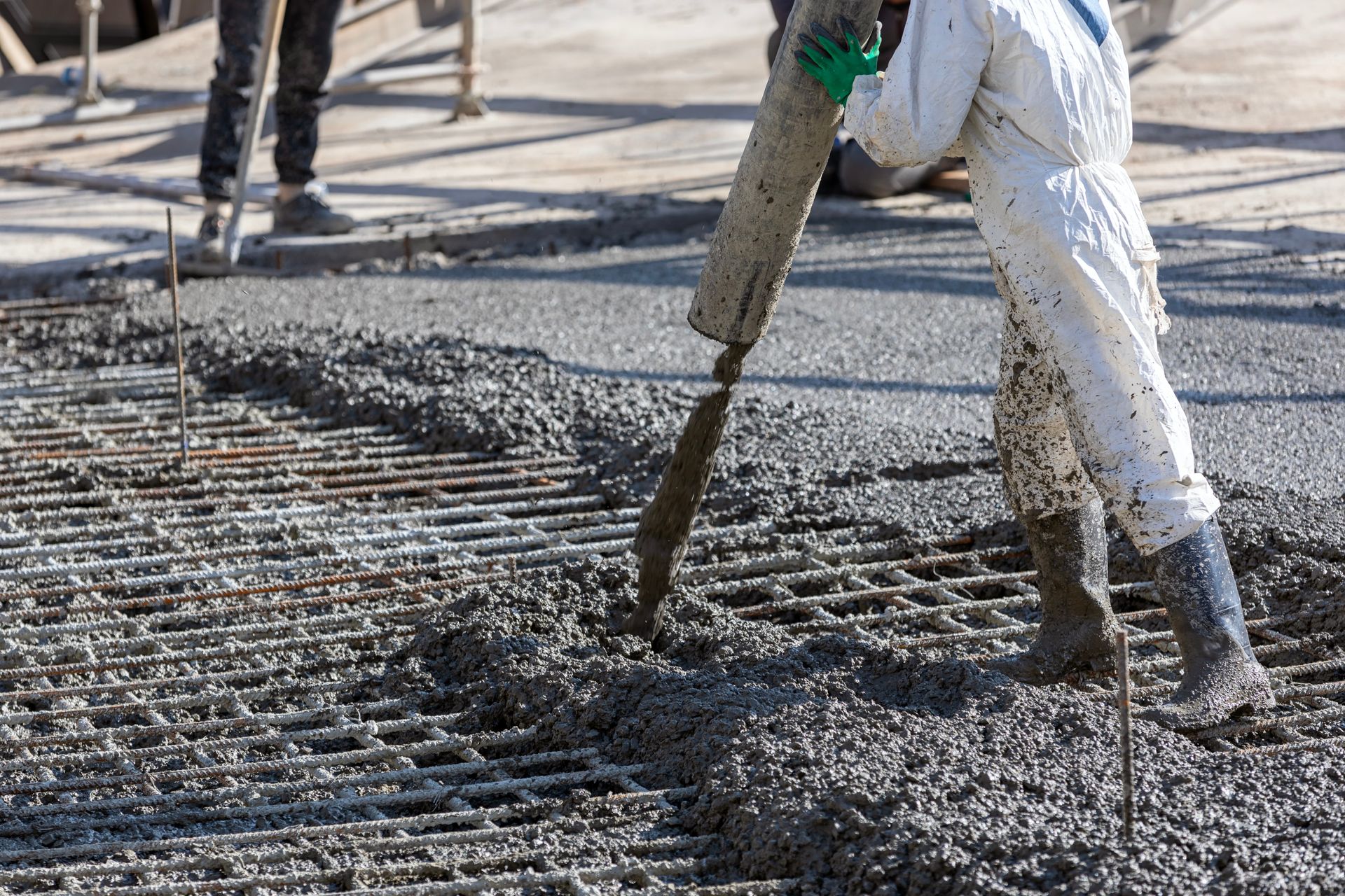 Professionnels en combinaison faisant couler du béton sur une armature en métal