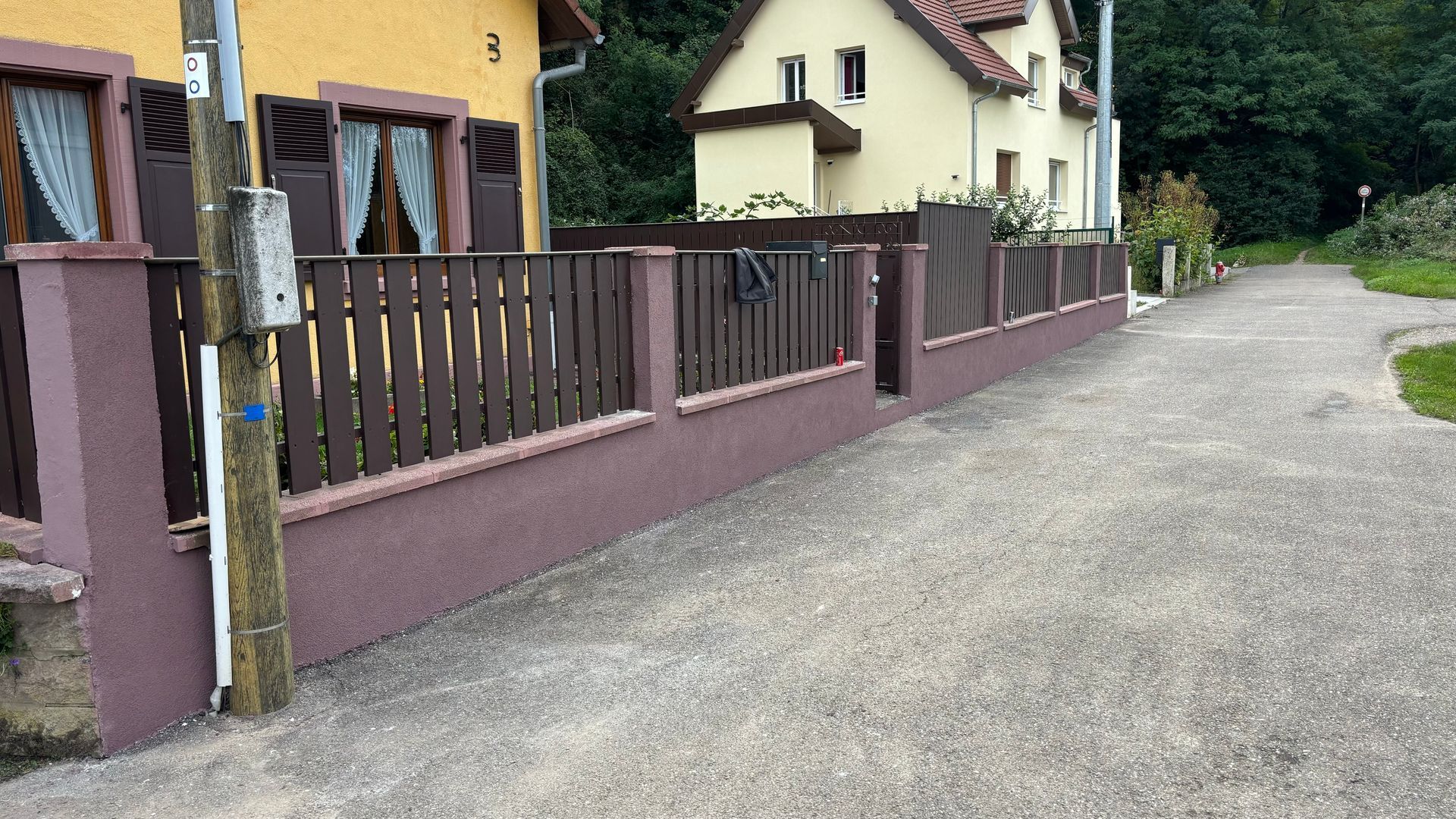 Nettoyage à haute pression d'un mur de soutènement en béton devant une maison.