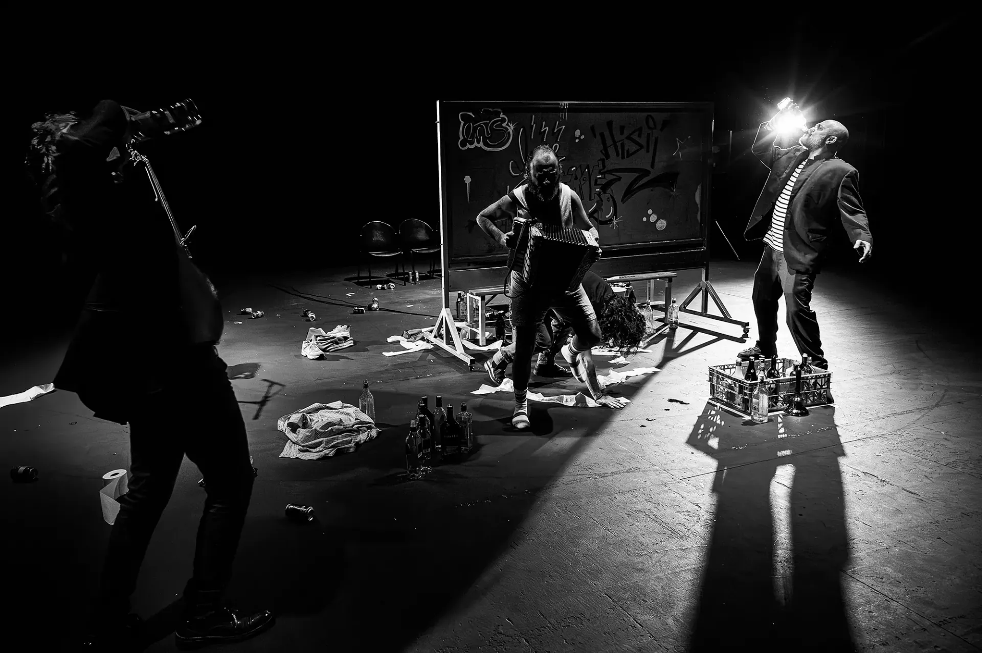 Fotografía en blanco y negro de tres personas bailando en un espacio oscuro con escombros y grafitis.