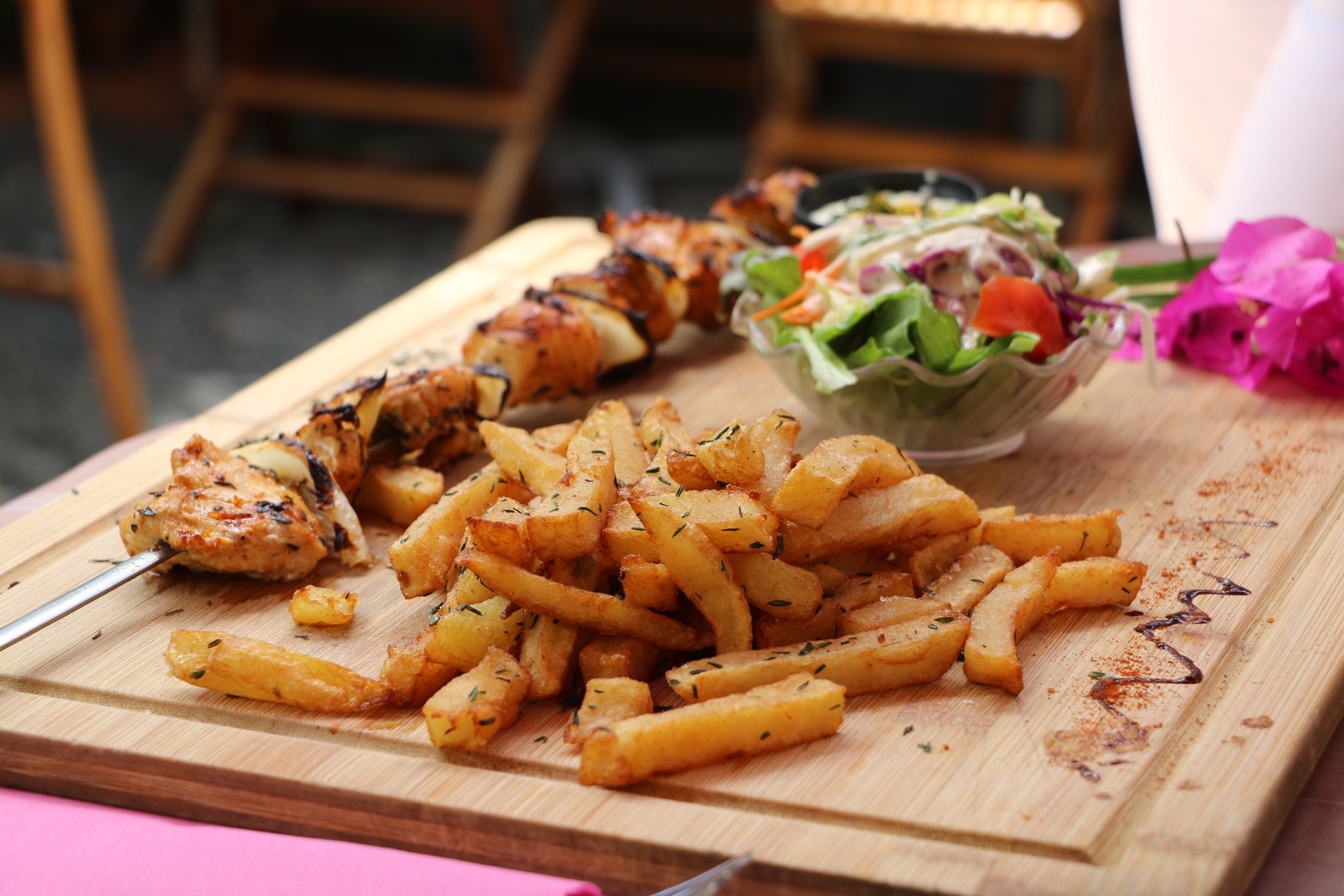 Assortiment d'entrées présenté sur une planche en bois, avec des frites et une petite salade, sur une table de restaurant