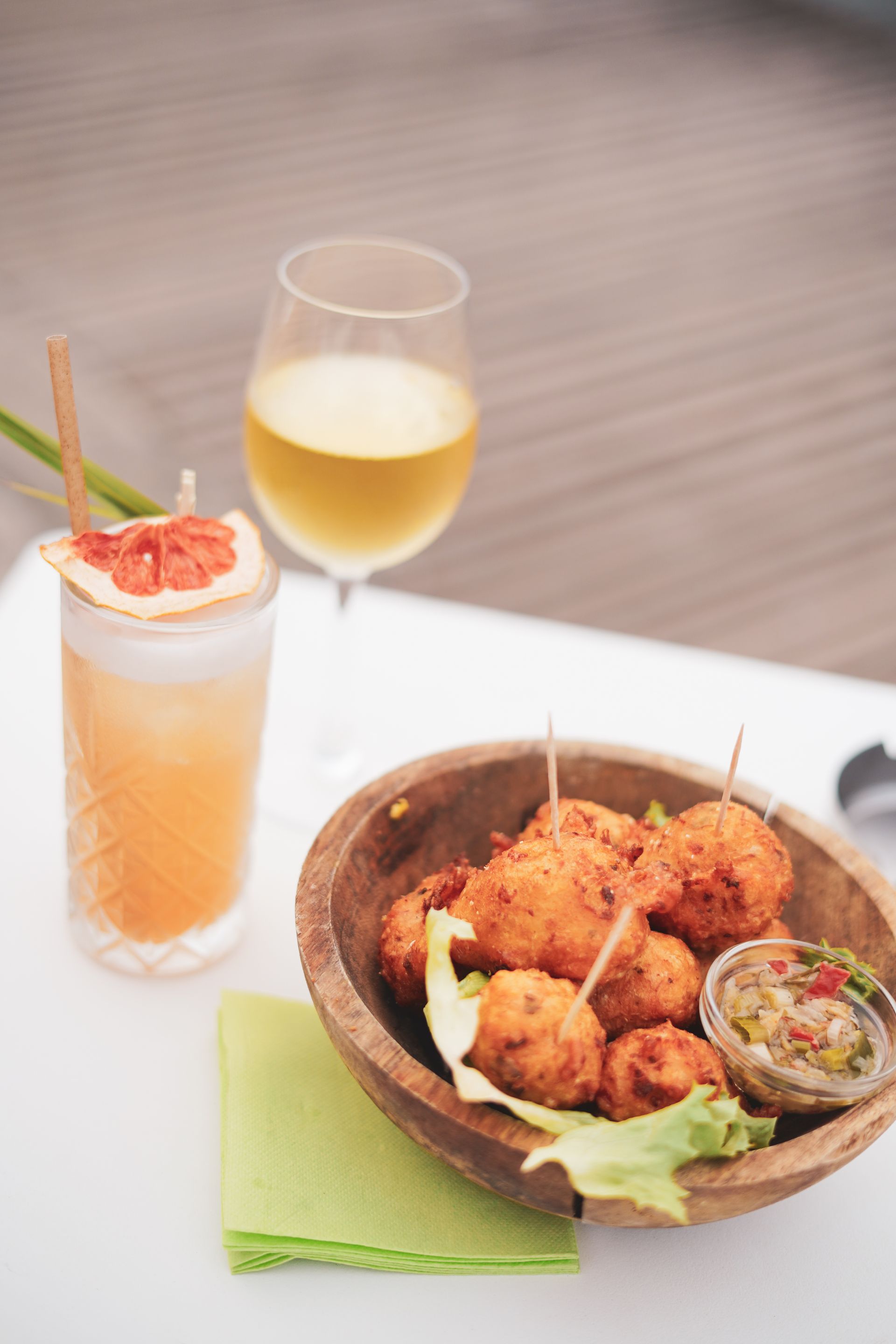 Deux cocktails et un bol d'amuse-gueules frits sur une table blanche avec une serviette verte