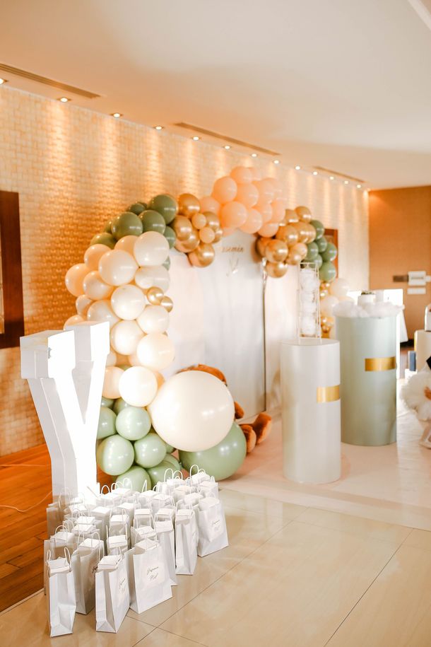 Arche de ballons blancs et verts et boîtes cadeaux dans une salle de réception à l'éclairage chaleureux