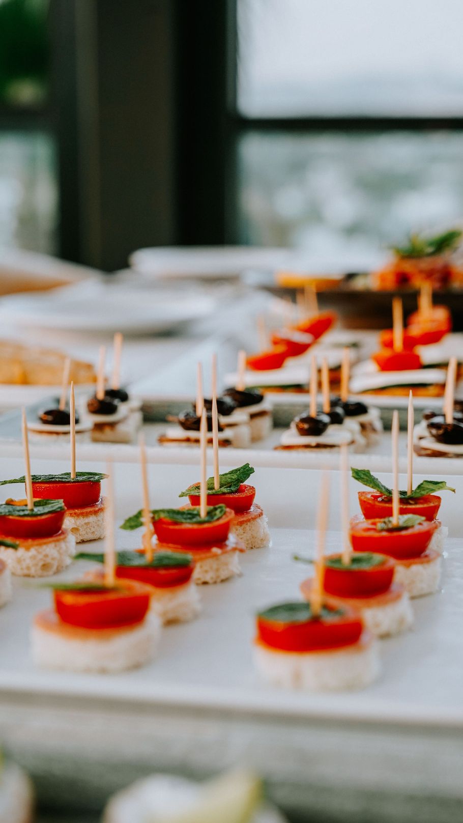 Plateau de bouchées apéritives garnies de sauce rouge, présentées sur des cure-dents et disposées sur une table de buffet.