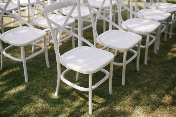 Des rangées de chaises pliantes blanches disposées sur l'herbe pour un événement en plein air