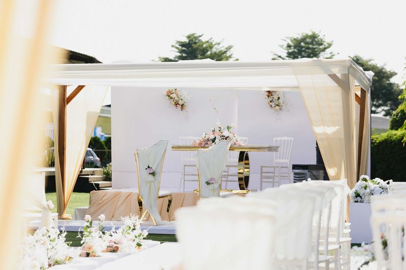 Réception de mariage en plein air avec des tentures blanches, une décoration florale et des tables dressées sous une canopée