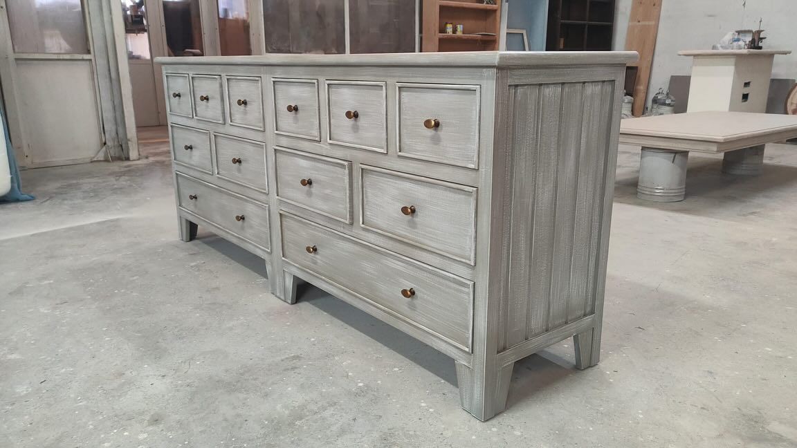 Cómoda de madera gris con numerosos cajones en una habitación.