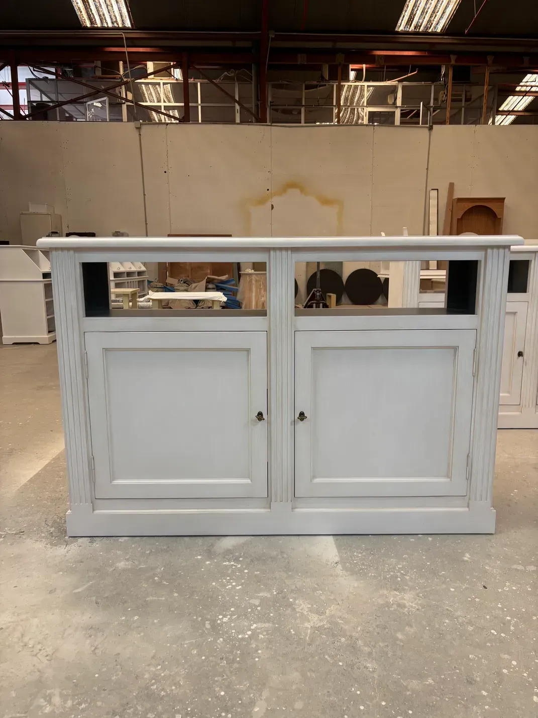 Mueble de madera gris con dos puertas y estantes abiertos.