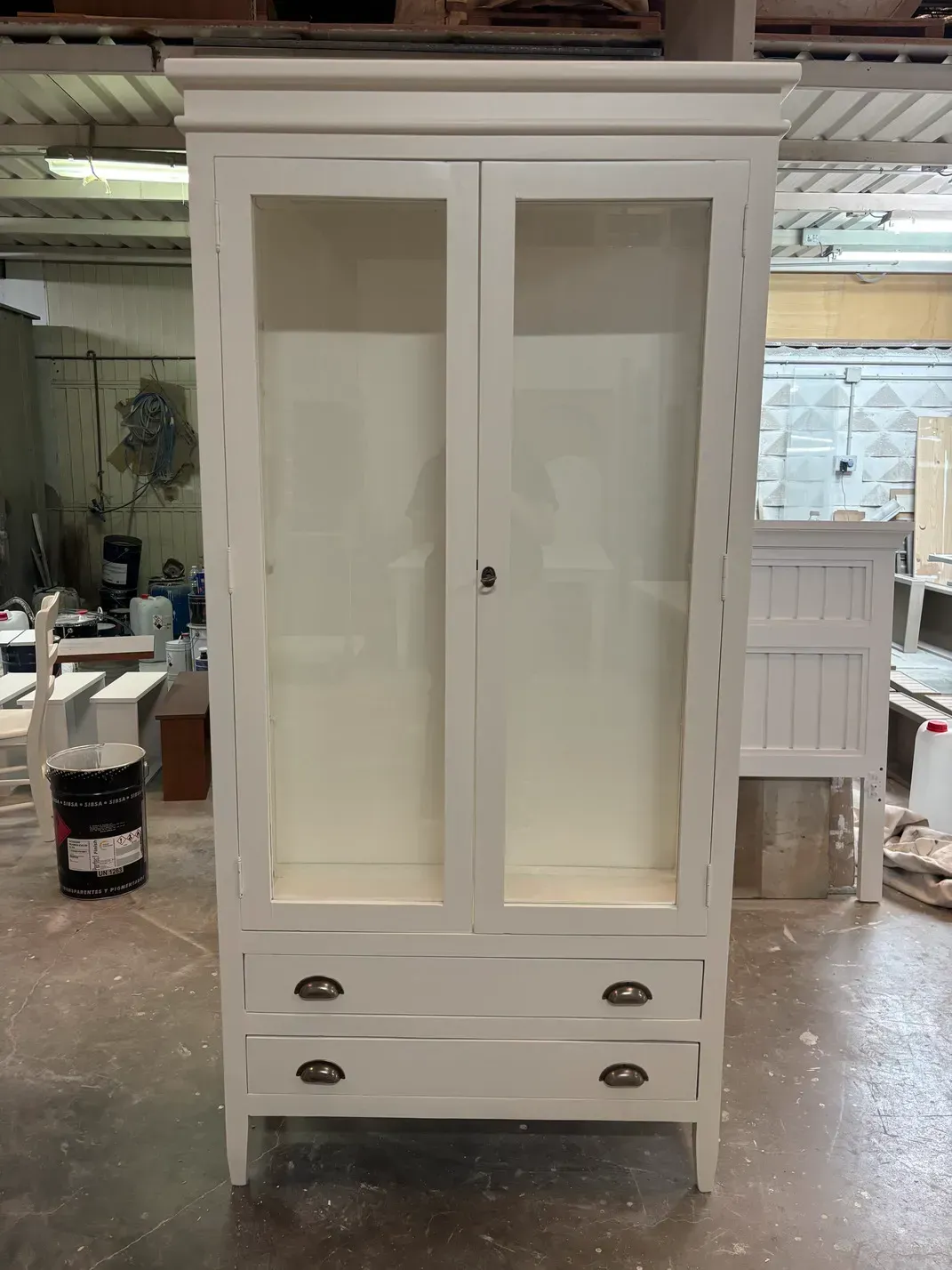 Vitrina de madera blanca con puertas y cajones de cristal.