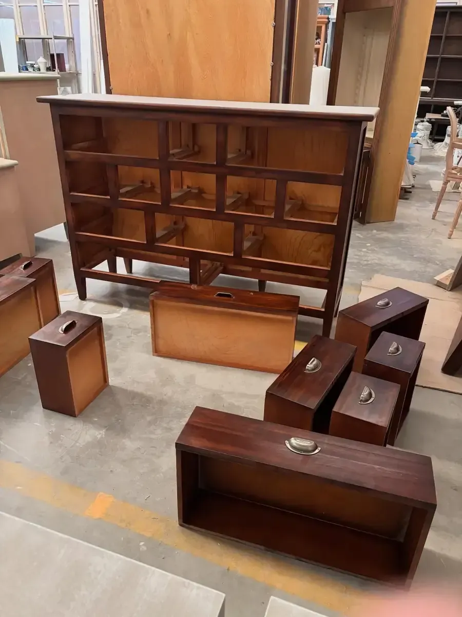 Pintor en una escalera de mano aplicando pintura a una pared en un pasillo interior.