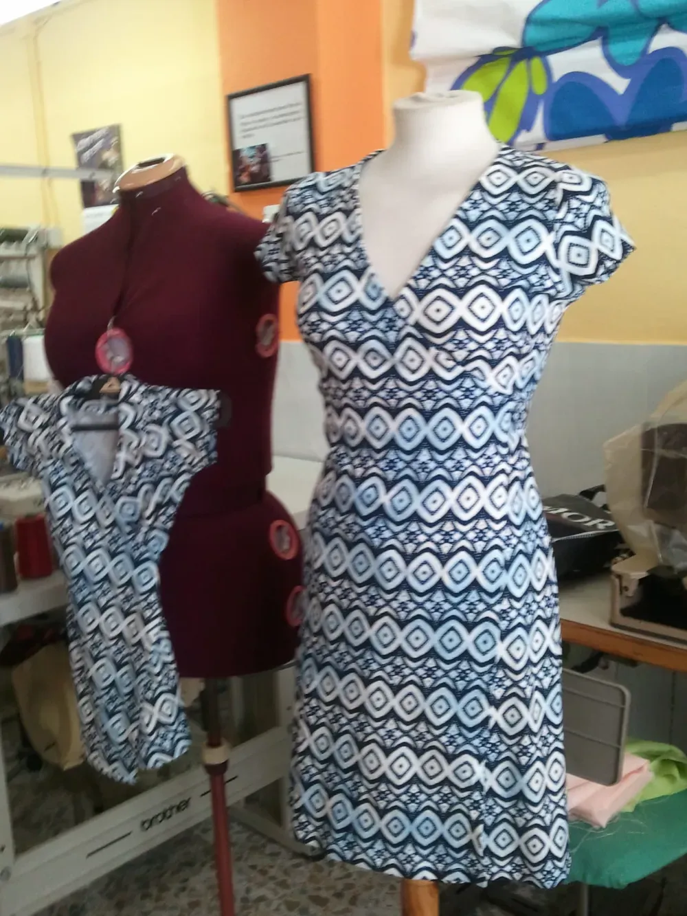 Maniquí con vestido estampado en azul y blanco, otro maniquí y vista parcial de un espacio de costura.