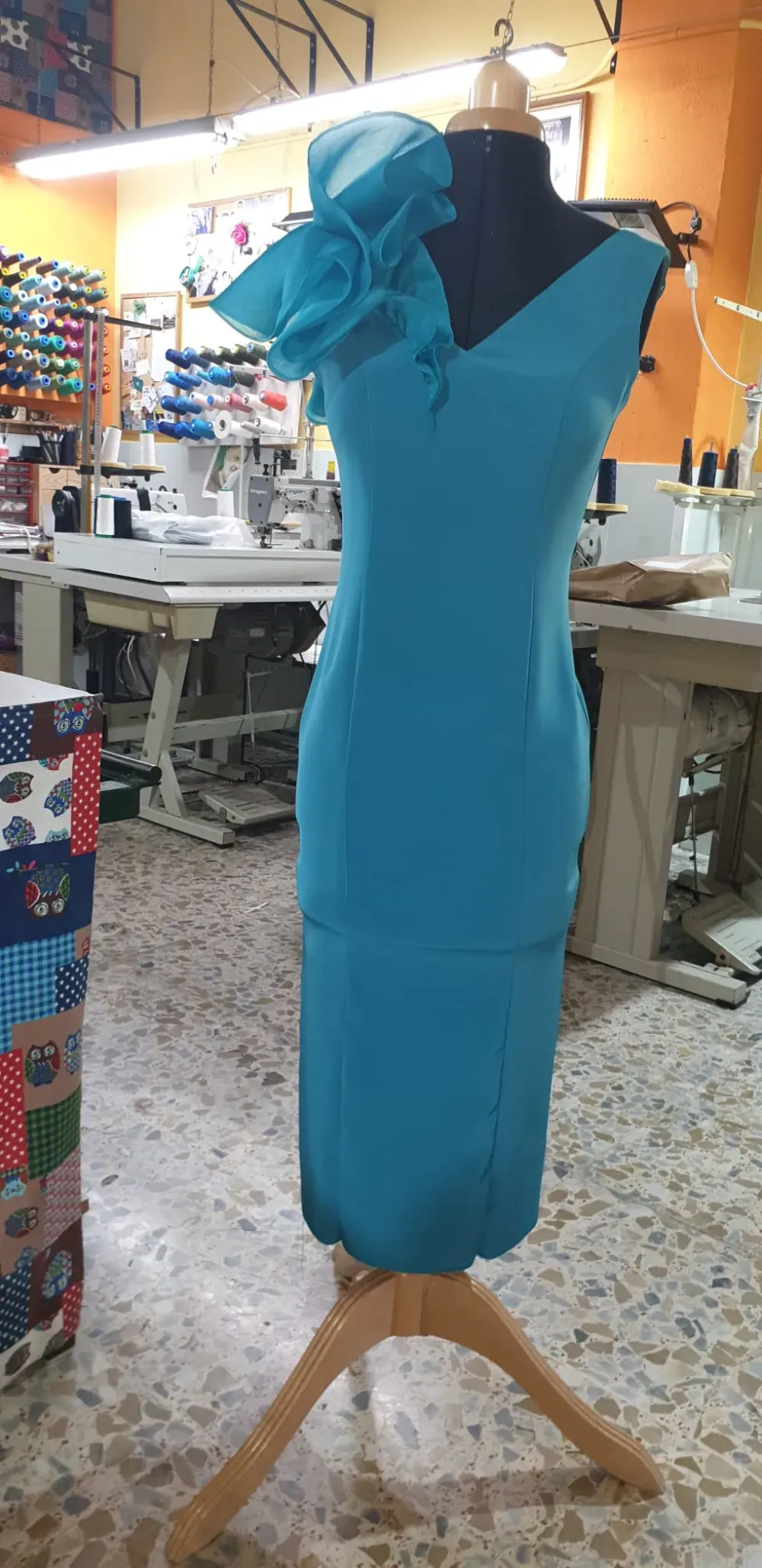 Un vestido azul sobre un maniquí con un sombrero a juego. El maniquí está en un taller de costura.