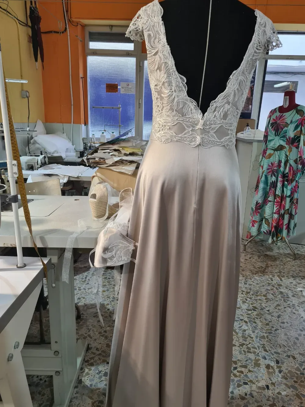 Vista posterior de un vestido de novia de satén sobre un maniquí en un taller. Cuerpo y botones de encaje.