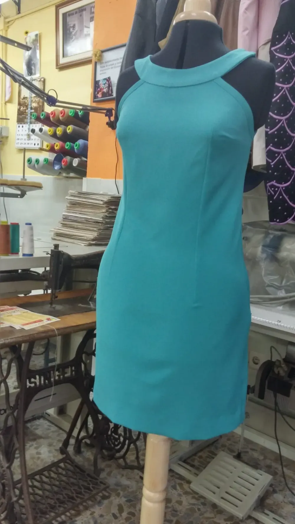 Vestido turquesa sobre maniquí en un taller de costura.
