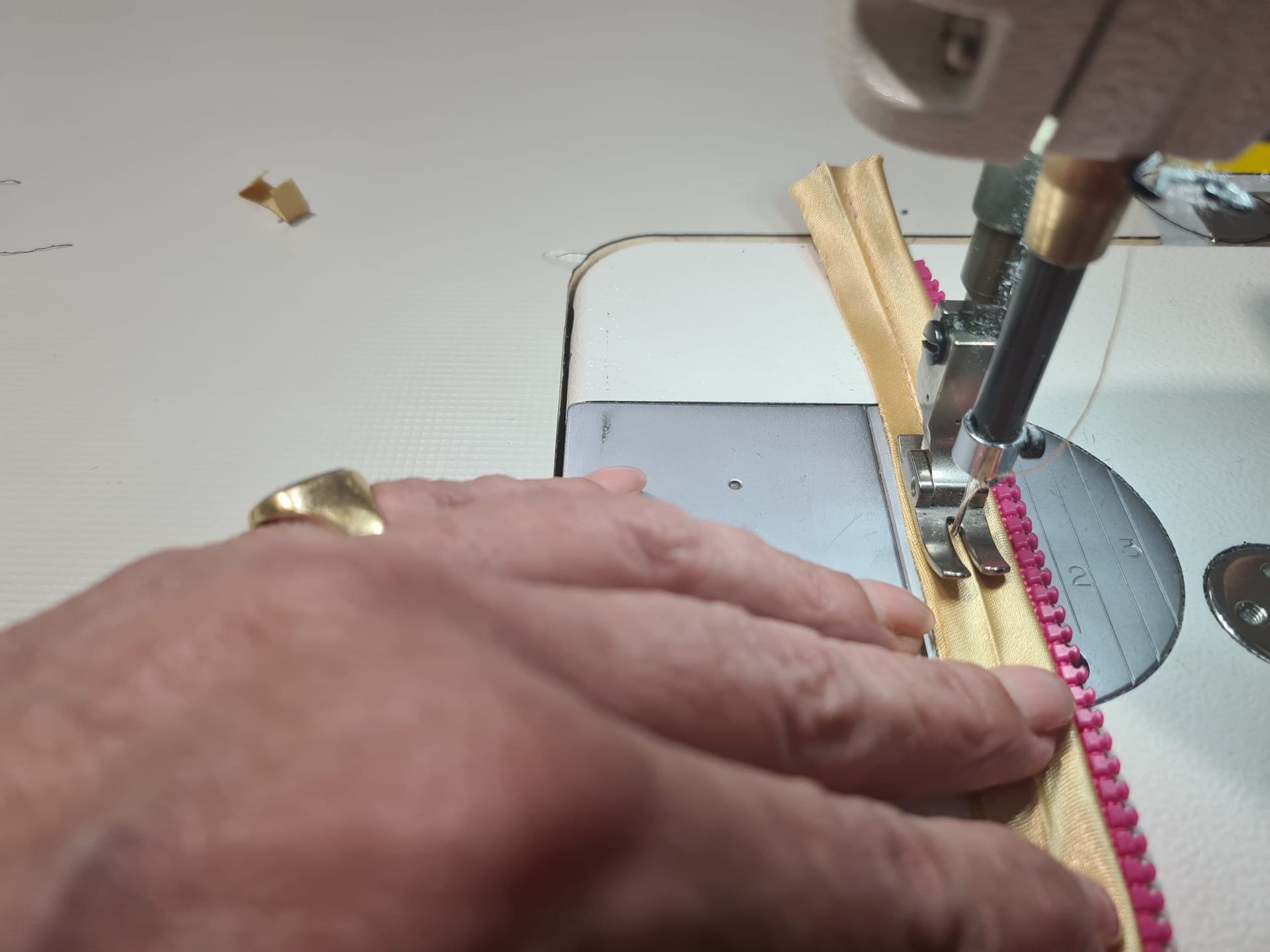 Persona cosiendo una cremallera a una tela con una máquina de coser.