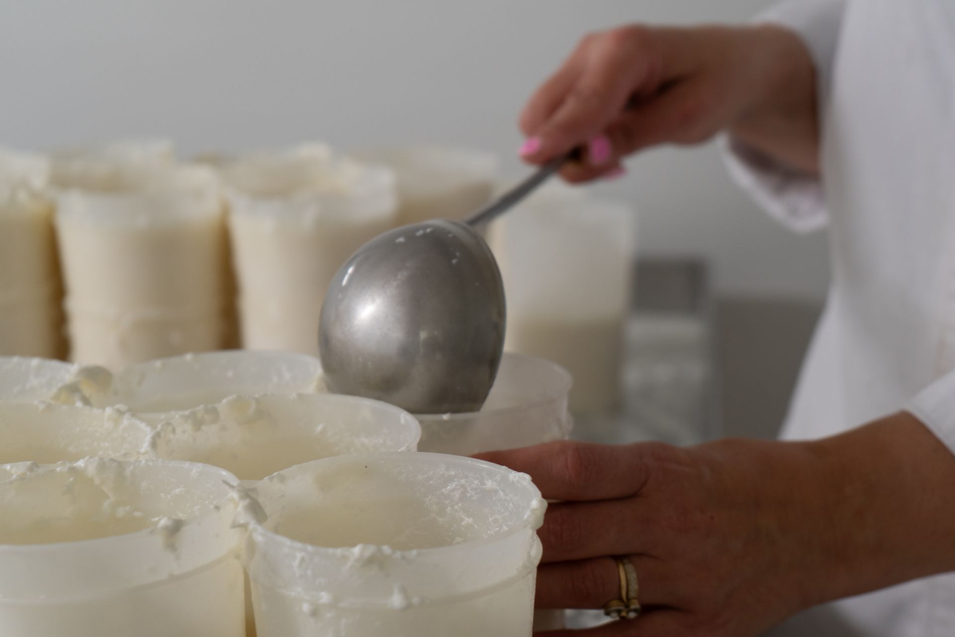 Une personne avec une louche, remplissant des pots.