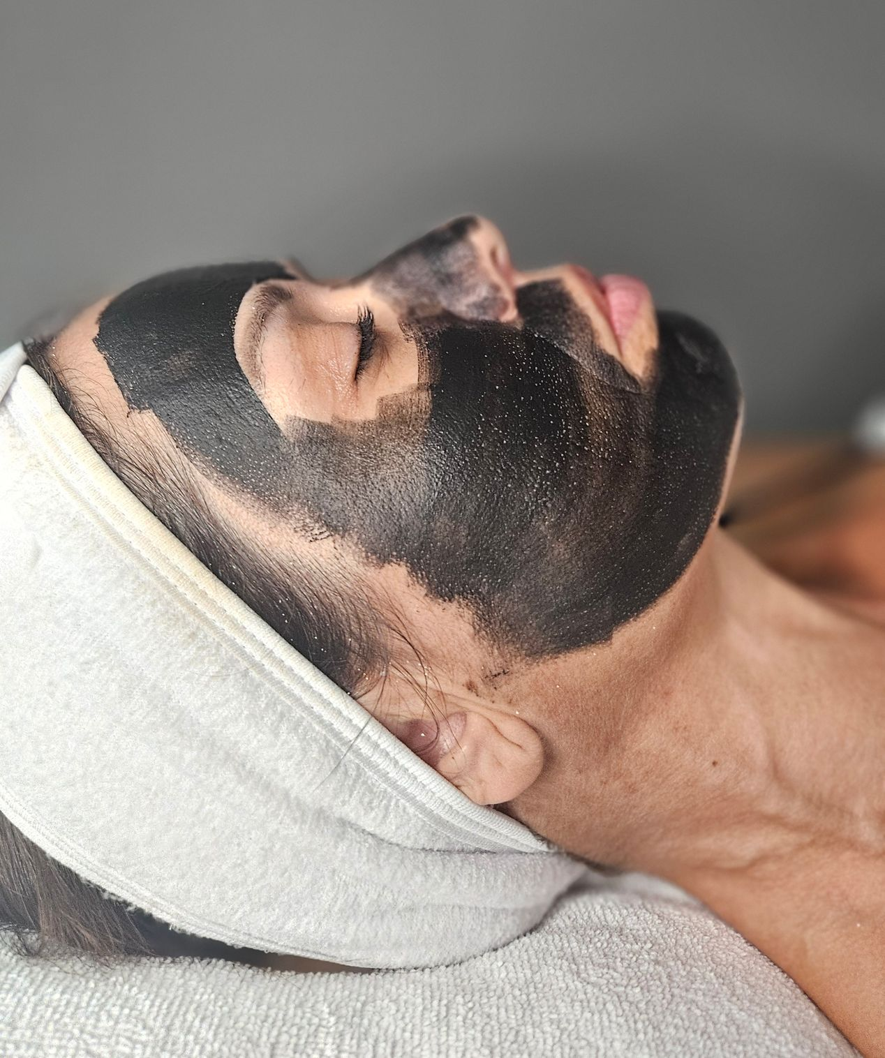 Persona que recibe un tratamiento facial de microcorriente; manos enguantadas de color azul utilizando el dispositivo en la cara.