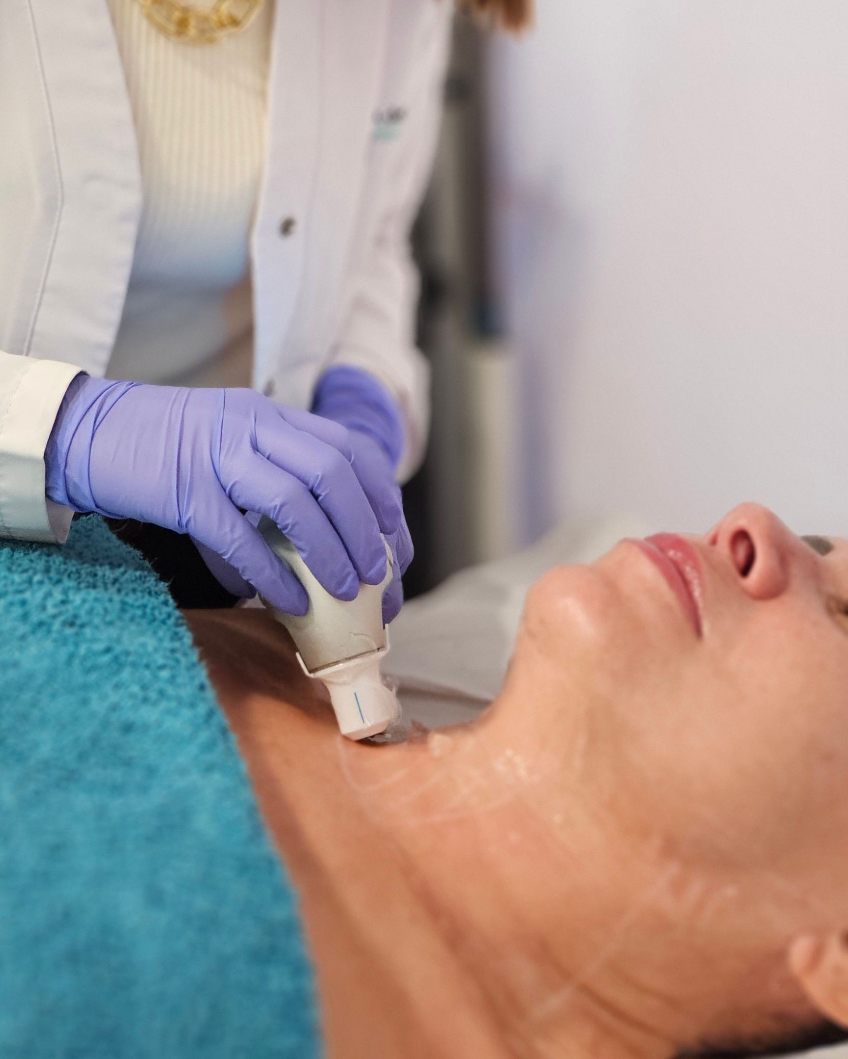 Persona con una máscara de carbón, usando protección para los ojos, recibiendo un tratamiento facial con láser en una clínica.