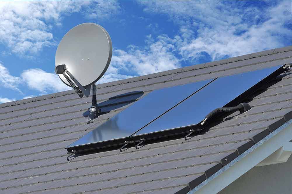 Auf dem Dach eines Hauses ist eine Satellitenschüssel montiert