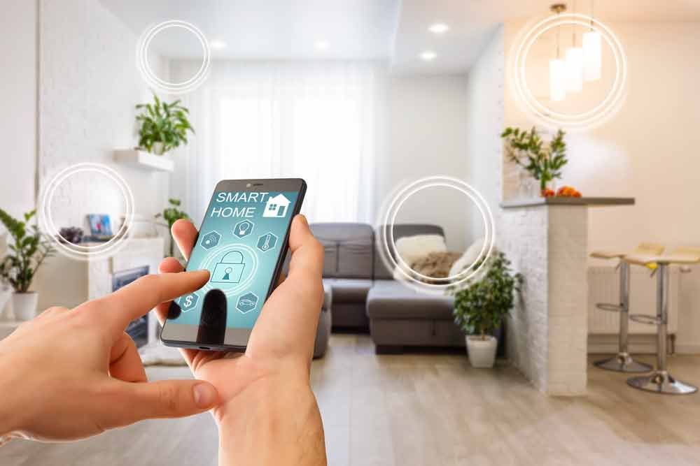 Eine Person hält in einem Wohnzimmer ein Smartphone in der Hand.
