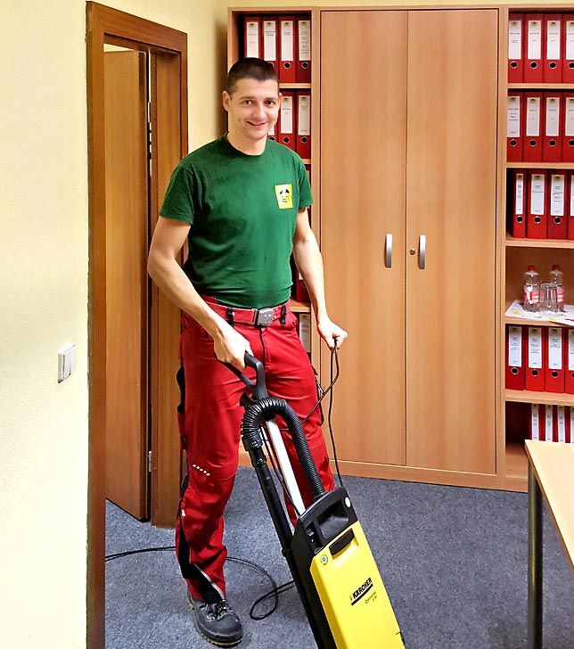 Reinigungskraft staubsaugt einen Teppich