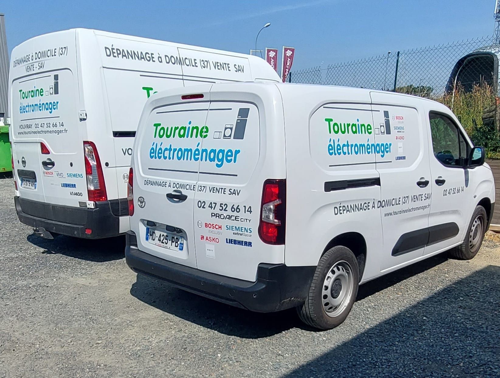 Deux fourgonnettes blanches portant le logo de l'entreprise Touraine Électroménager garées sur du gravier en plein jour.