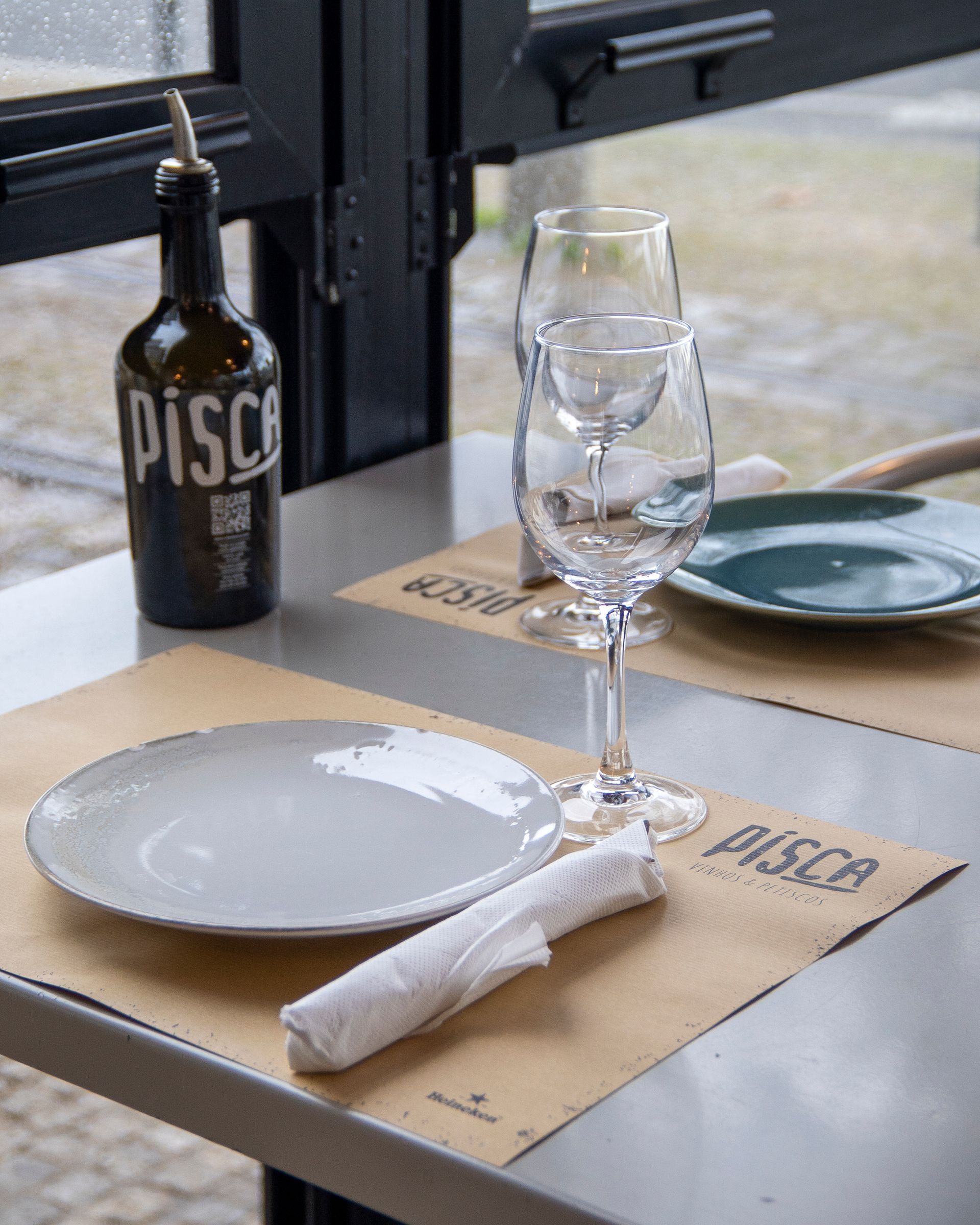 Uma mesa com pratos, copos e uma garrafa de pisco.