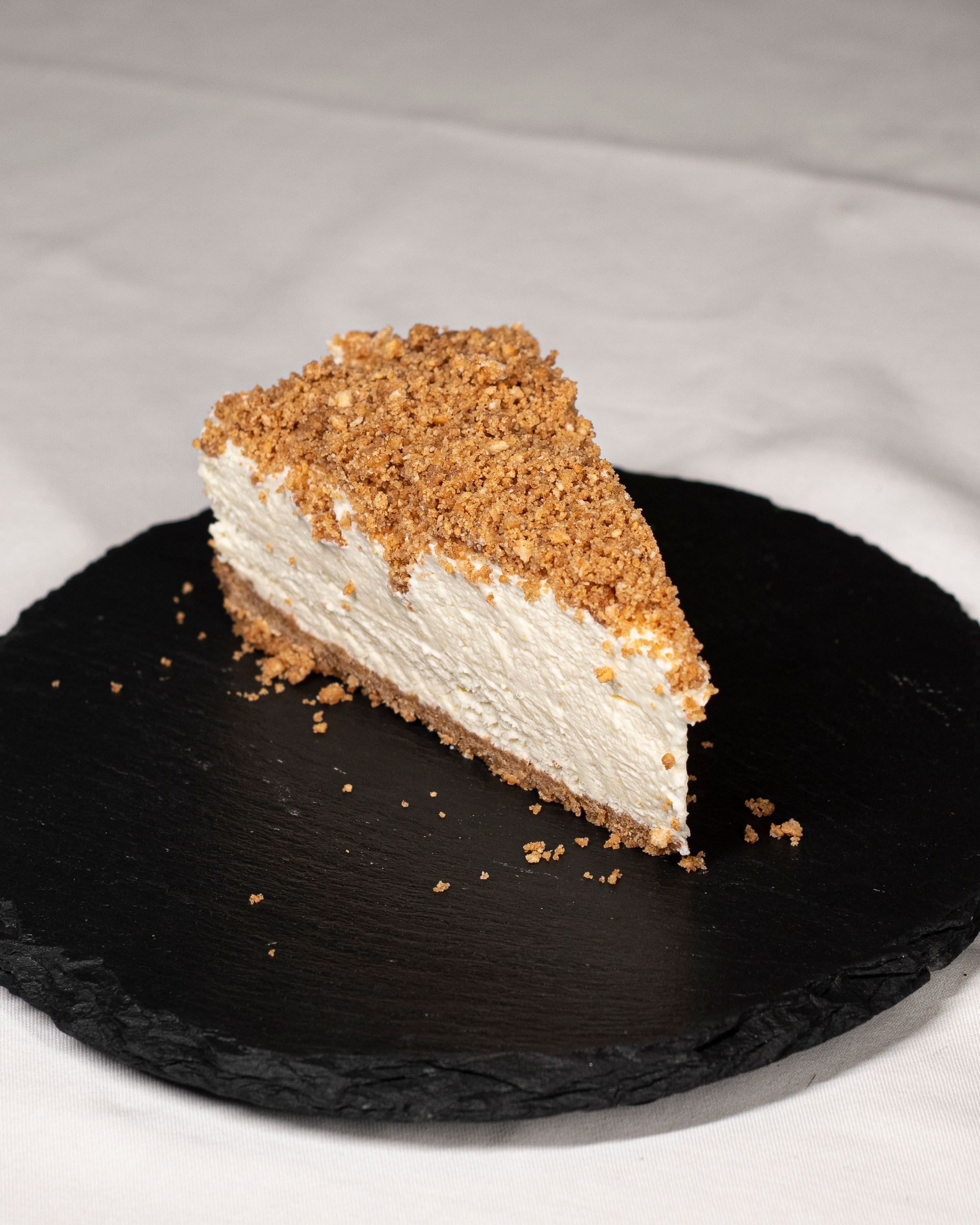 Uma fatia de cheesecake está em um prato preto.