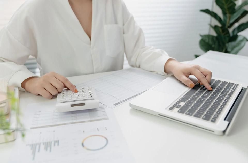 Evelin Buck Steuerberatung, Frauenhand tippt auf Taschenrechner, andere Hand auf Laptop-Tastatur