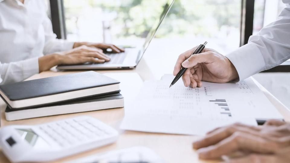 Evelin Buck Steuerberatung, Frauenhand unterschreibt Unterlagen am Tisch