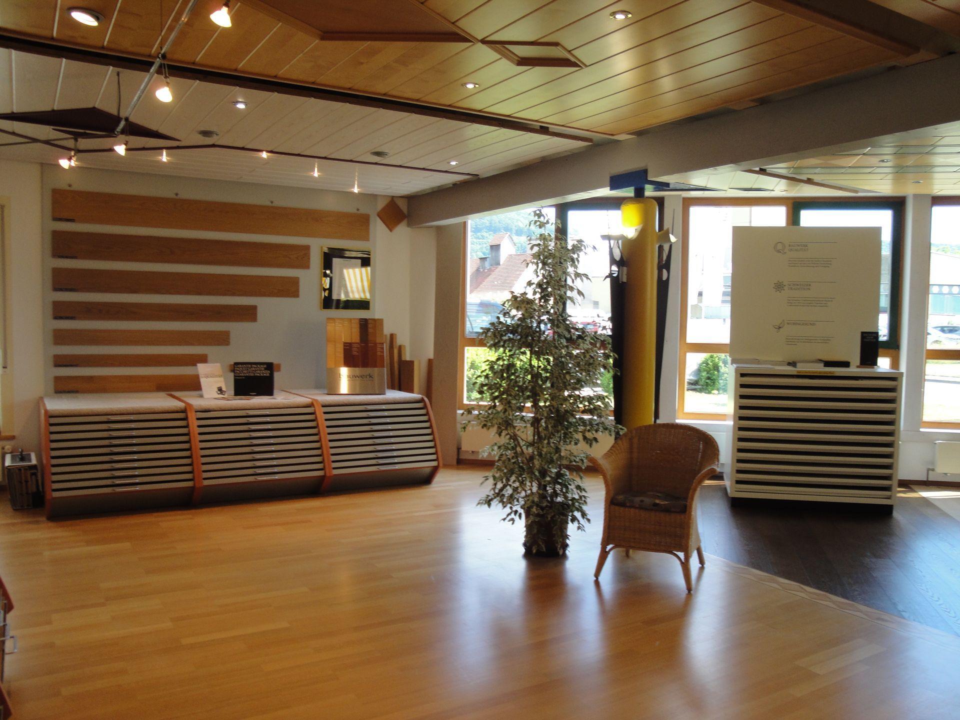 Innenraum mit Holzboden, Materialstapeln und einer dekorativen Pflanze.