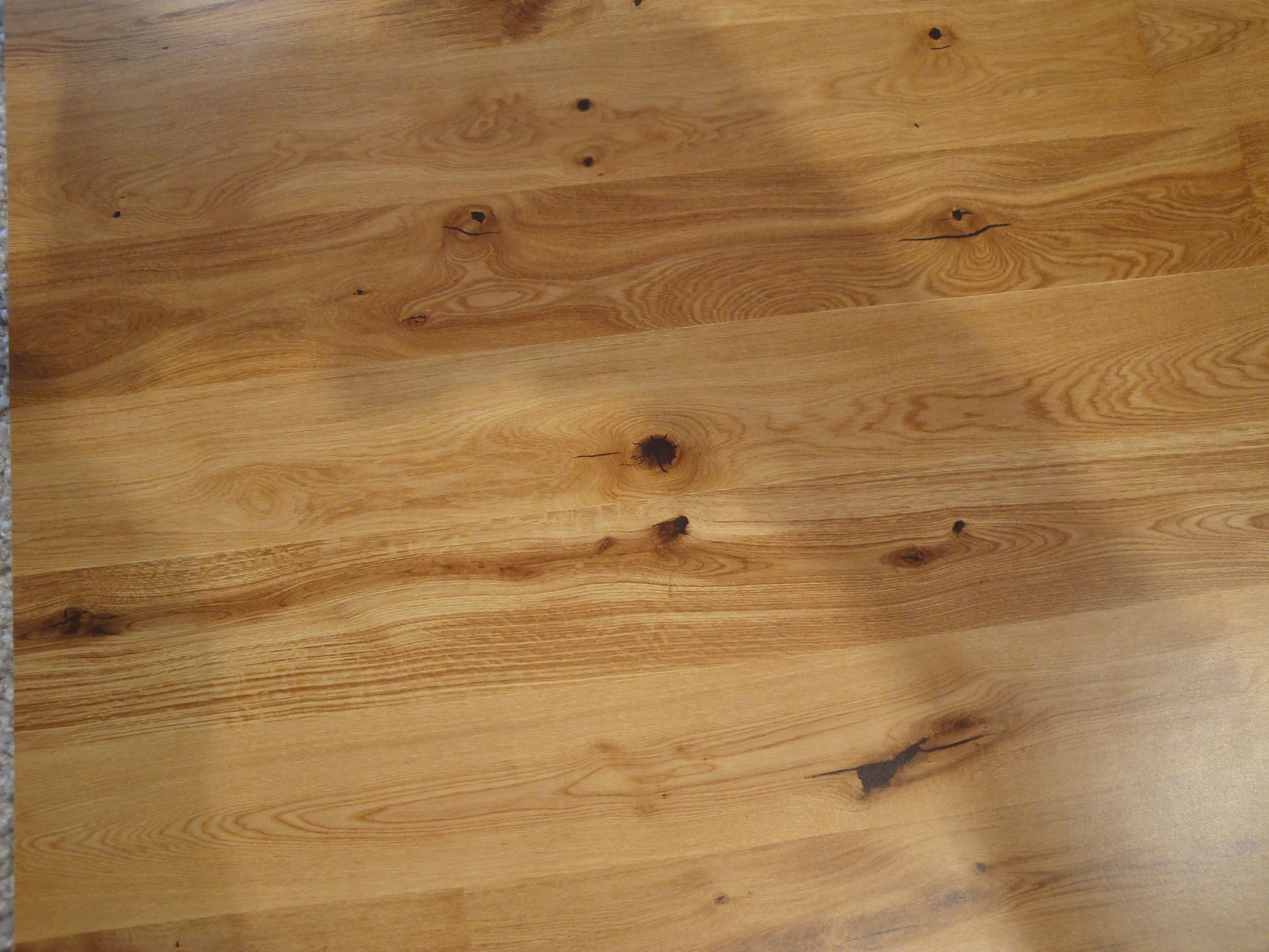 Holztischoberfläche mit hellbrauner Maserung und dunklen Astlöchern.