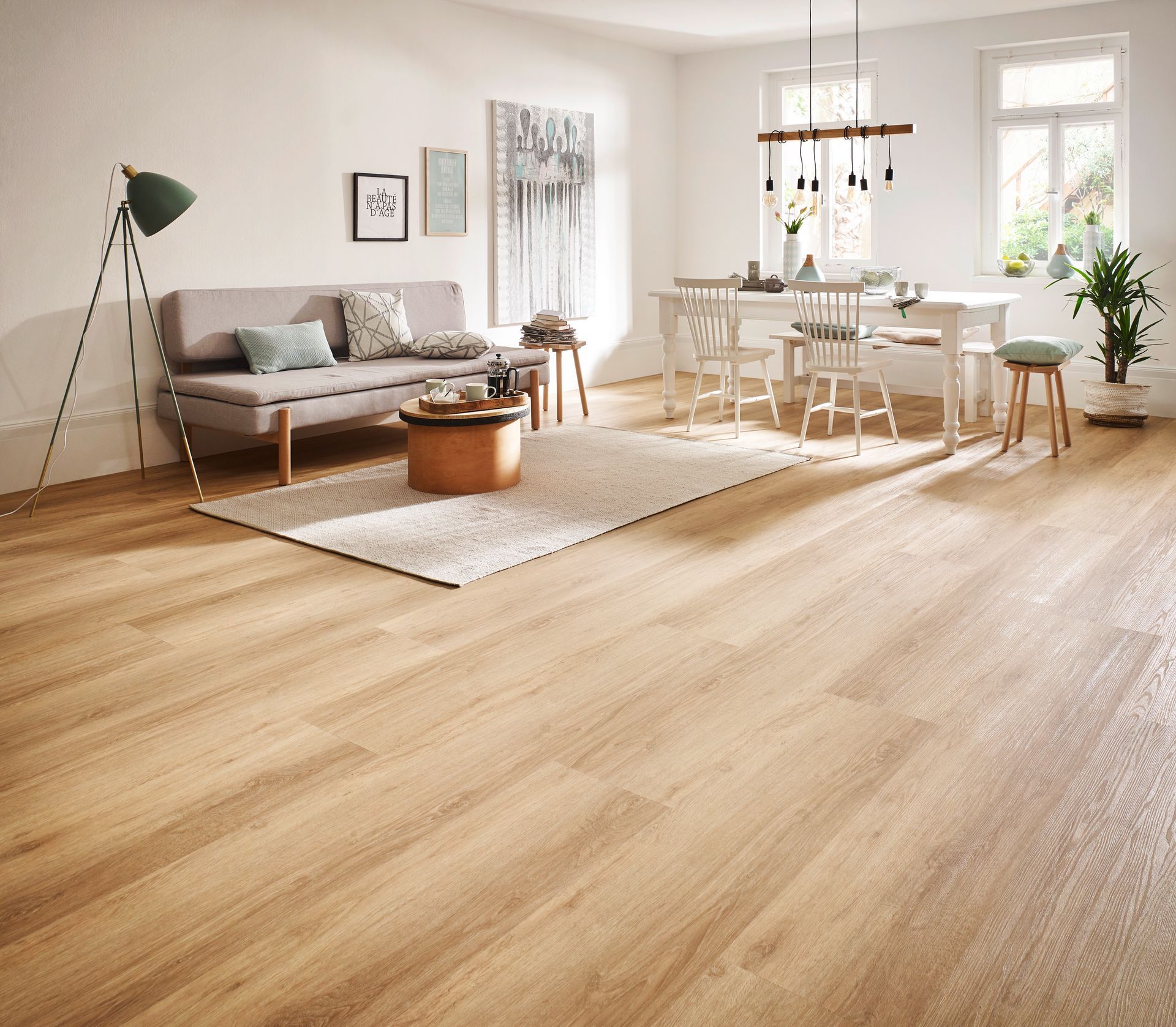 Wohnzimmer mit hellem Holzboden, Sofa, Teppich, Esstisch und Dekoelementen.