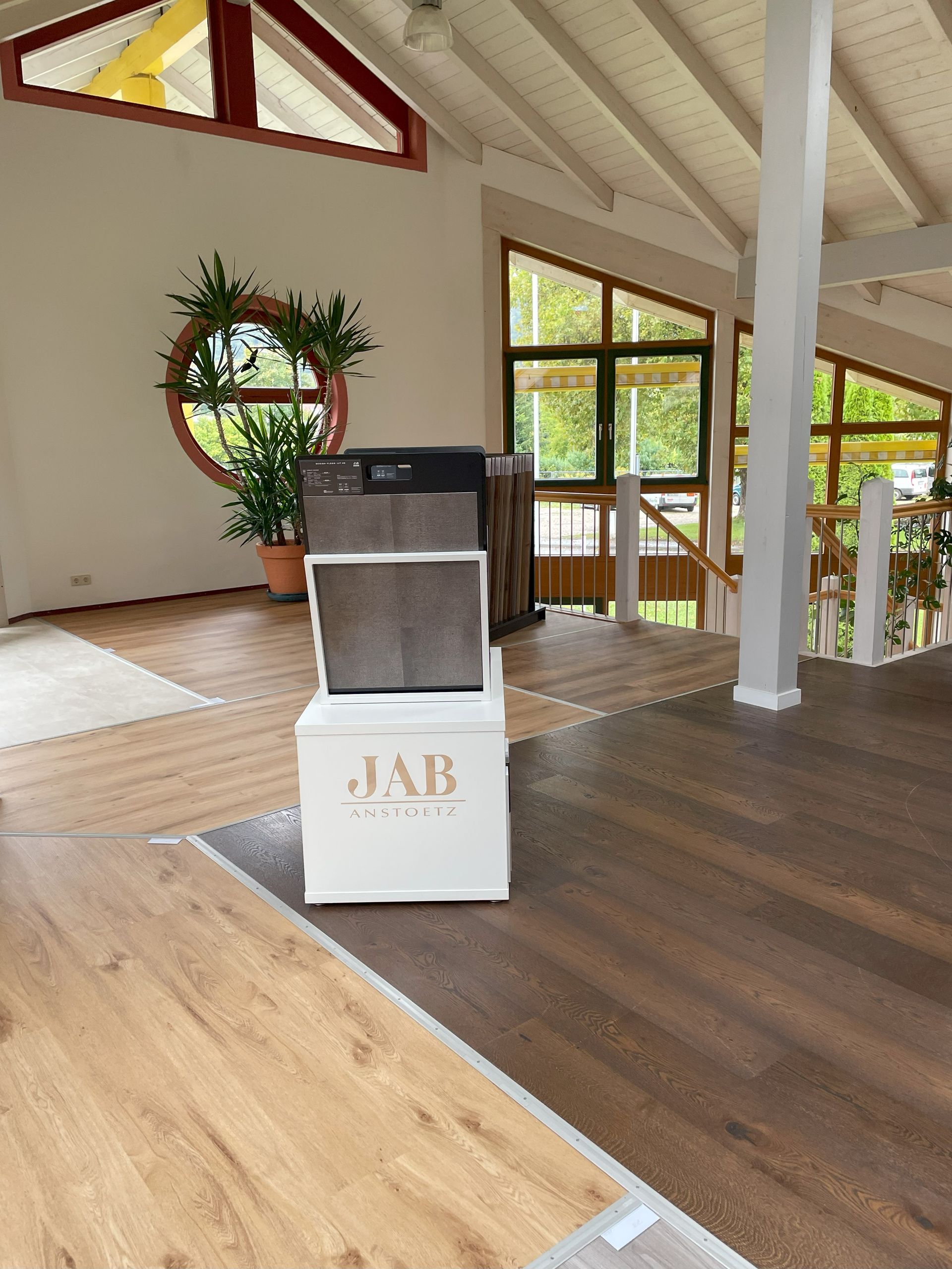 Zimmer mit Holzboden, Mustern und offener Treppe, natürliches Licht durch die Fenster.