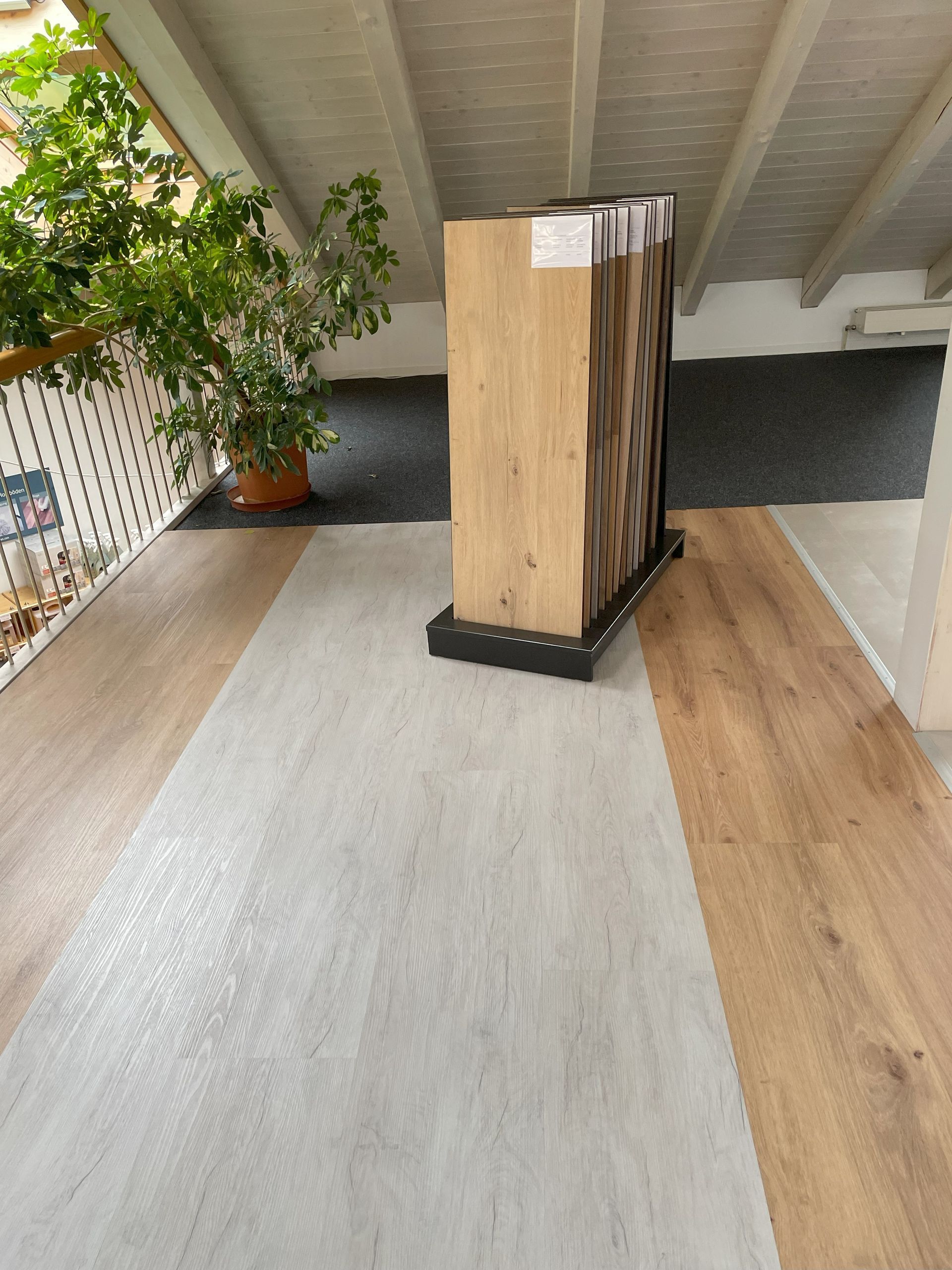 Bodenbelagsmuster werden auf einem hellen Holz- und Grauboden in einem Ausstellungsraum ausgestellt.