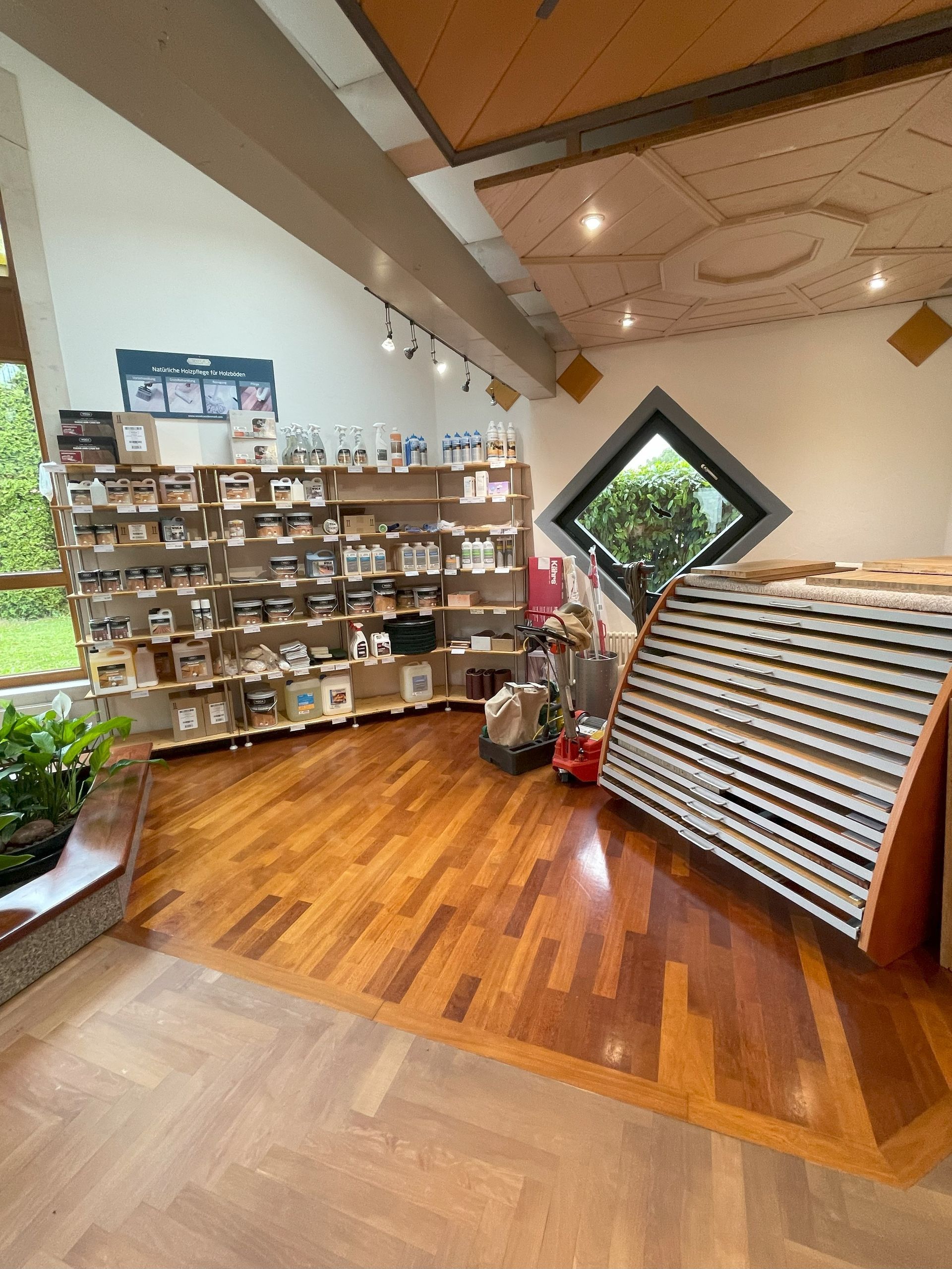 Ladeneinrichtung mit Holzböden und Regalen zur Produktpräsentation. Schräges Fenster und Holzdecke.