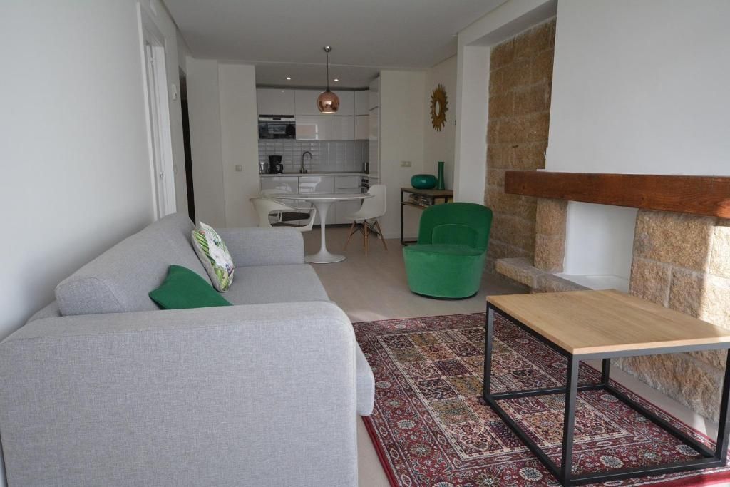 Sala de estar con sofá, alfombra, sillón, chimenea y cocina.