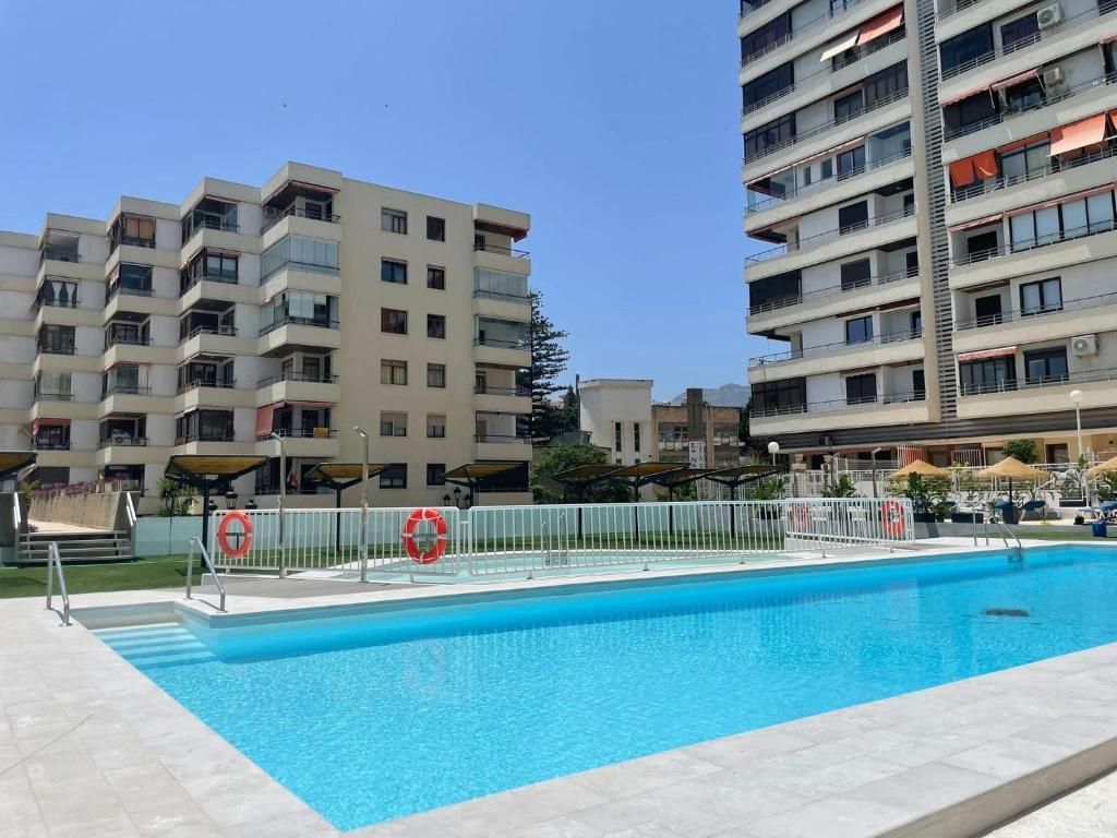 Piscina frente a edificios de apartamentos en un día soleado.