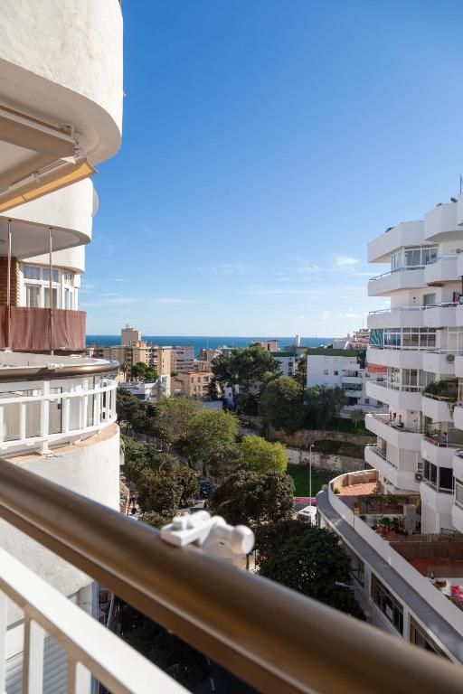 Vista de playa con arena, océano, palmeras y una cerca blanca bajo un cielo crepuscular.