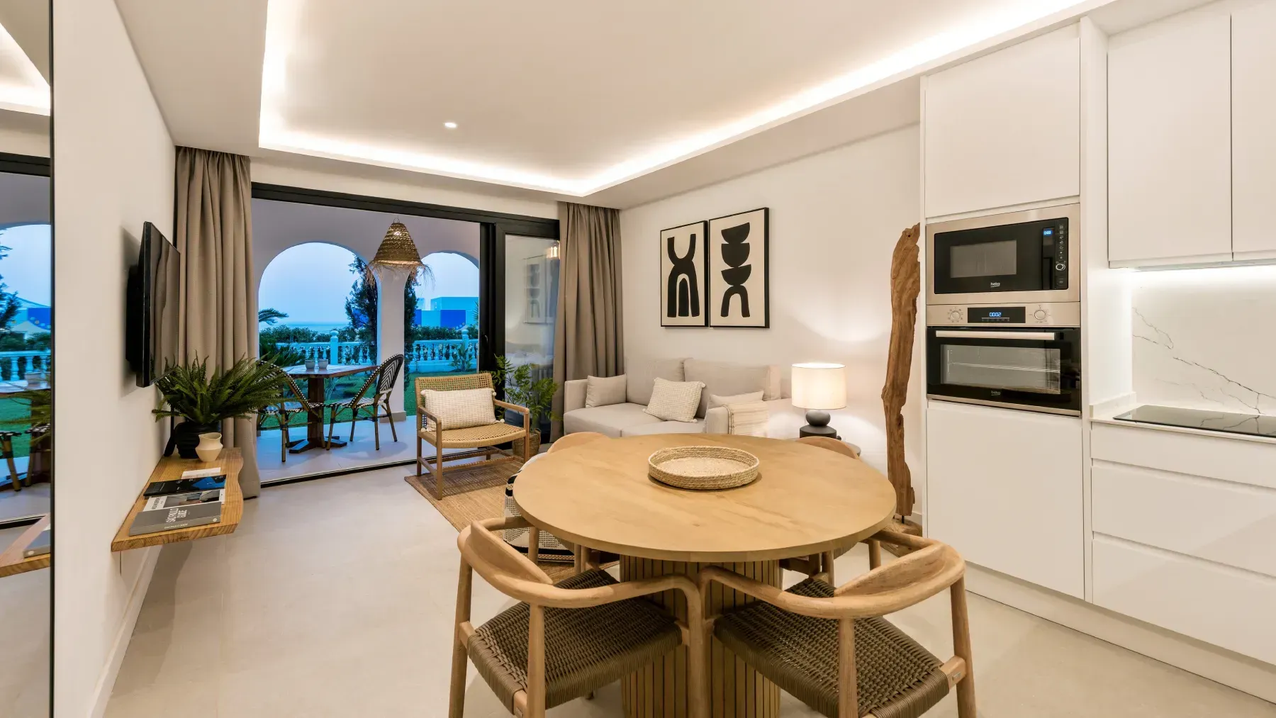 Moderna sala de estar con cocina abierta y comedor, tonos neutros y acceso al balcón.