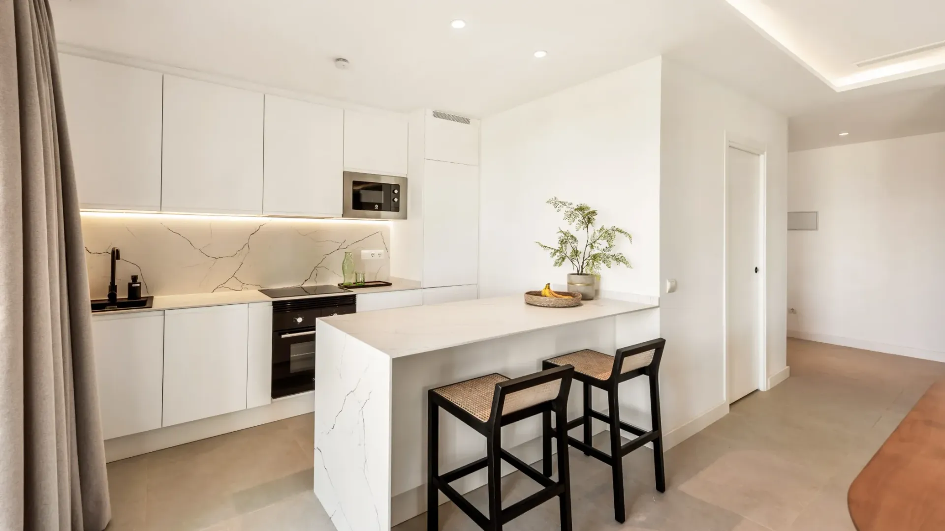 Cocina moderna blanca con península y dos taburetes bar.